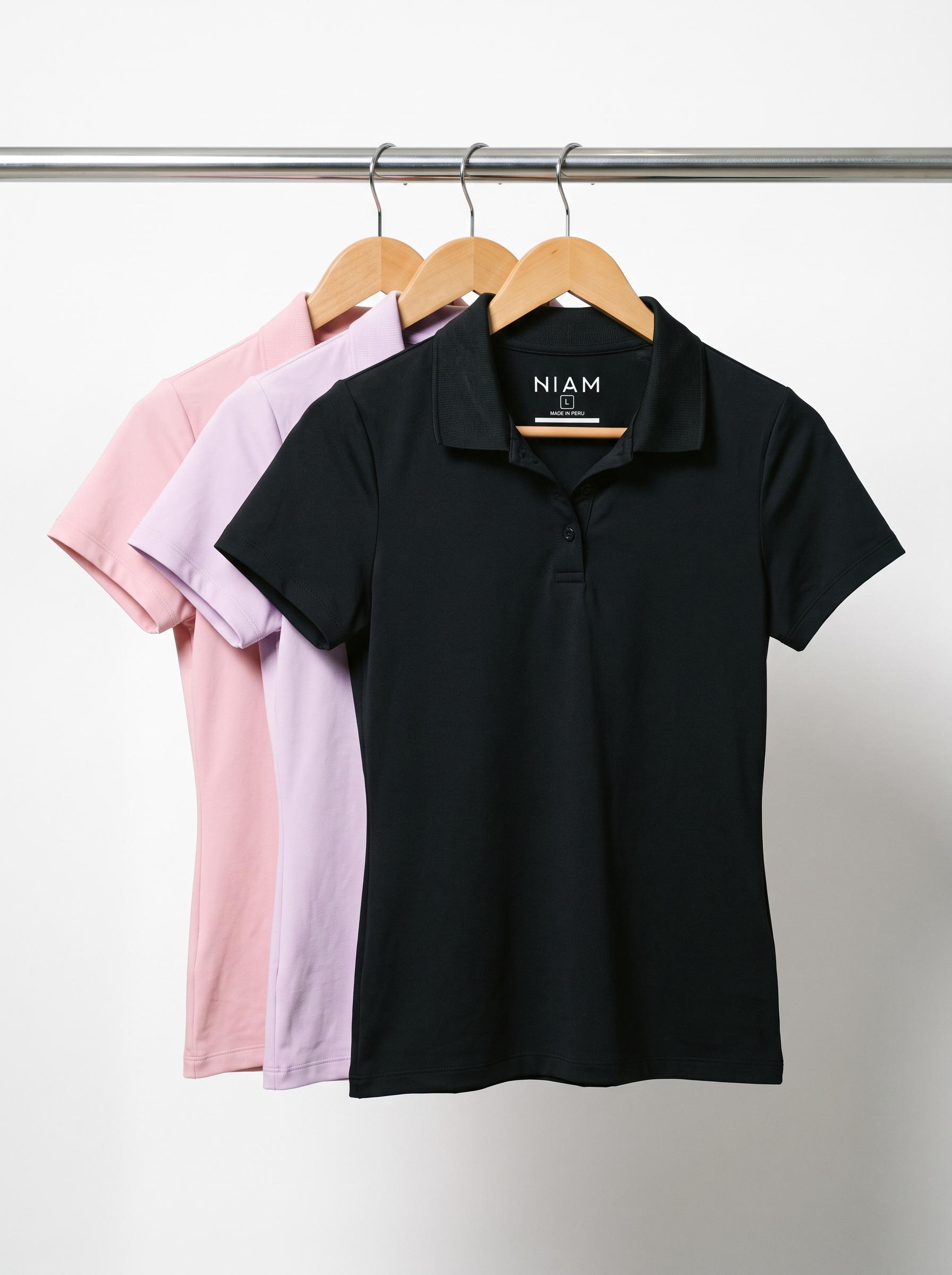 Three women's SwingFree performance polos on a studio rail
