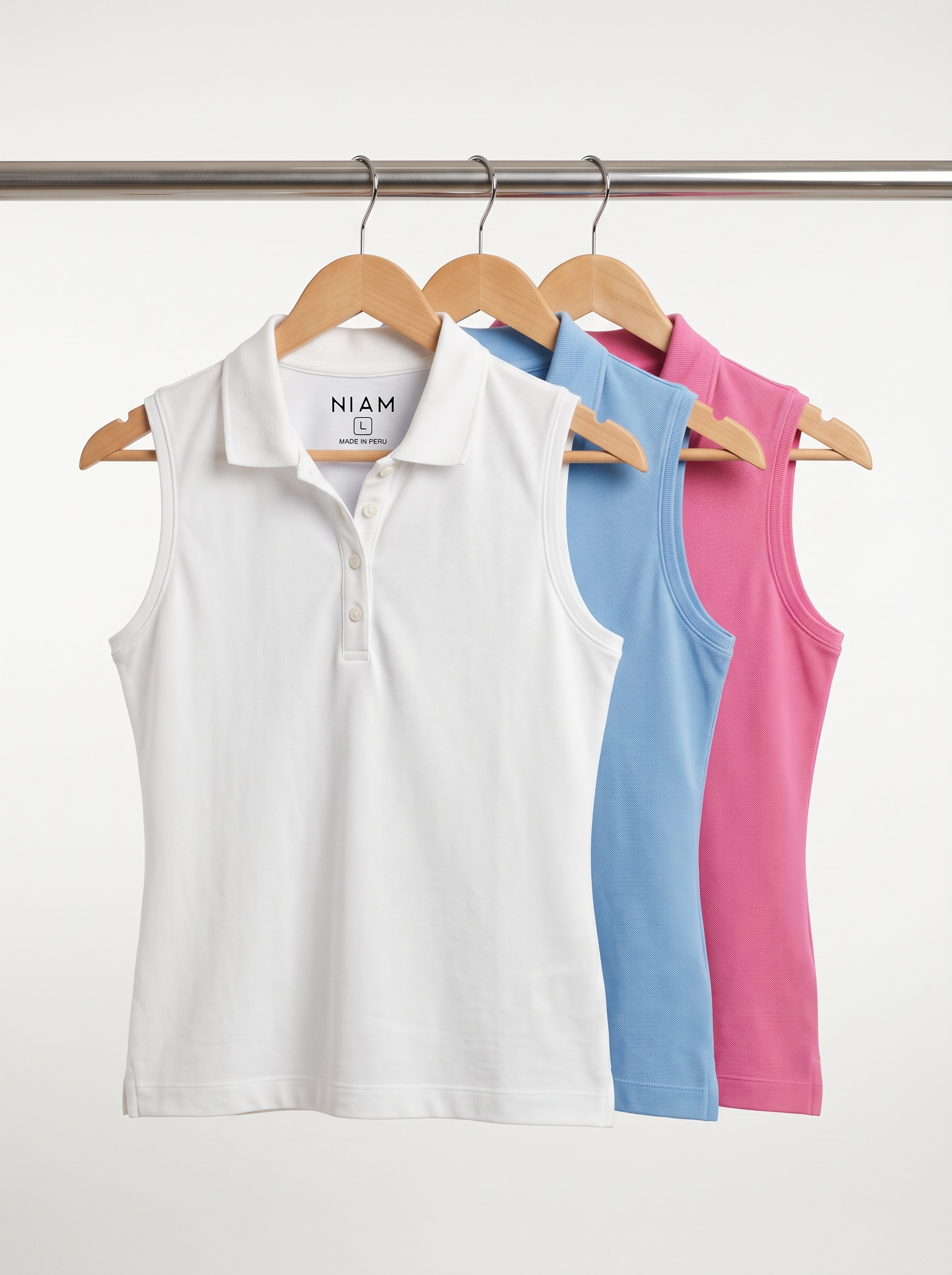 Three women's sleeveless pique polos on a studio rail